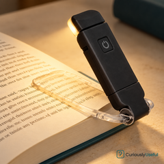 Black folding clip-on book light illuminating an open book.