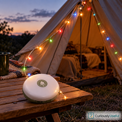 Colourful camping string lights around a tent with the rechargeable circular reel on a timber table.
